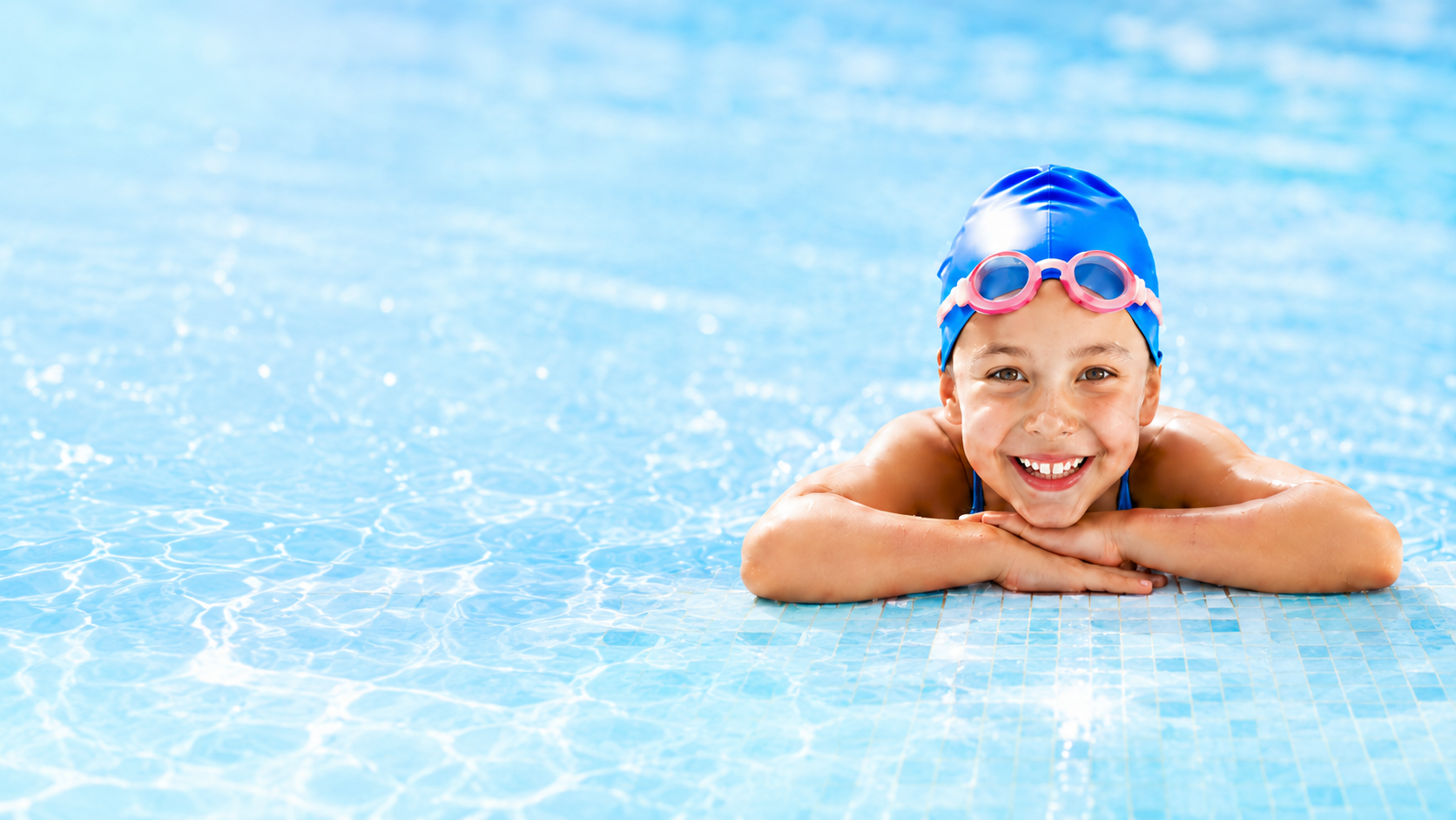 Young swimmer smiling at the edge of a pool